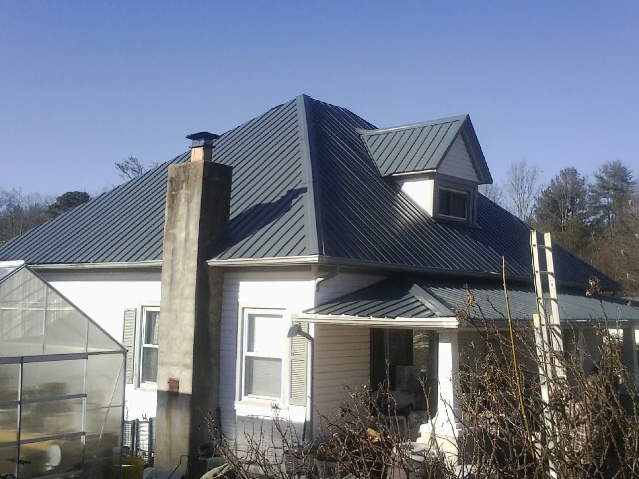 Dark blue standing seam metal roof on a white farmhouse with dormer — Slate & Tile Roof Repair by Roofing Brothers in Royse City