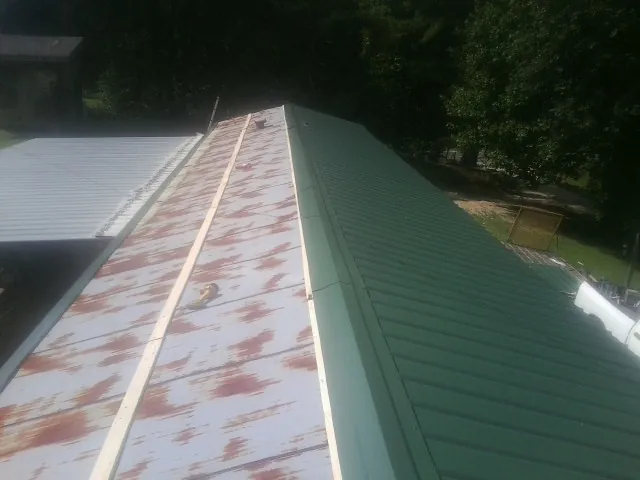 Old rusted panels beside newly installed green metal roofing — Wind Damage Roof Repair by Roofing Brothers in Royse City