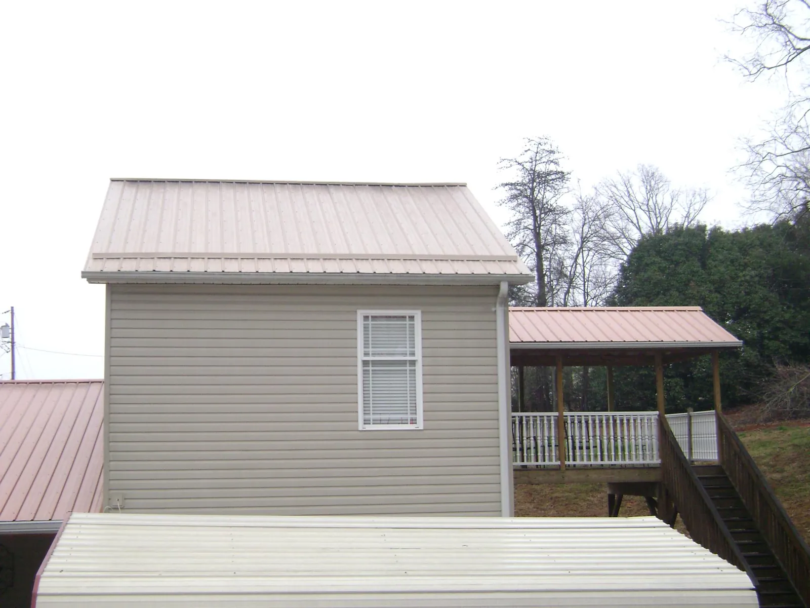 Tan metal roofs on a two story addition and attached porch, from a Roof Replacement job in Royse City