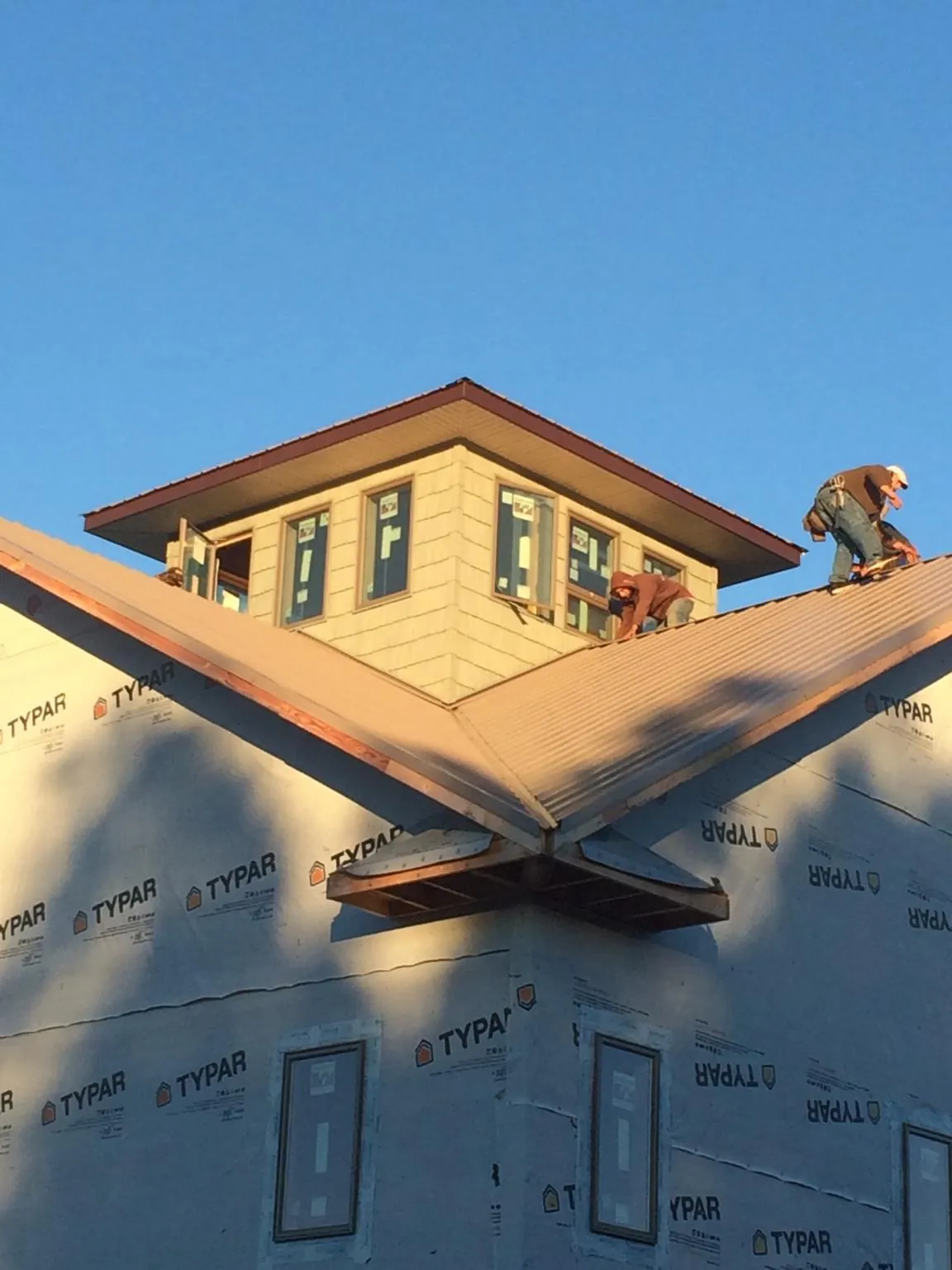 Roofers working around a rooftop cupola on a new metal roof at sunset — Roof Waterproofing in Royse City by Roofing Brothers